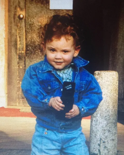 Raffaele Bottone da bambino, con un giubbotto di jeans e uno dei primi telefonini in mano